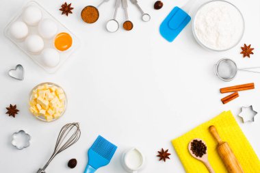 Arka plan ile yumurta pişirme, un, süt, baharat kakao, soda, anason, tarçın, Hindistan cevizi, tuz, kahve çekirdekleri ve mutfak araçları oklava, tahta kaşıklar, çırpma, elek, eşya şekil çerez kesici beyaz arka plan üzerinde pişirin.