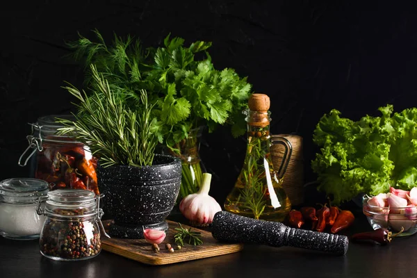 Harç ve dibekler ahşap kesme tahtası kavanoz marul yaprakları siyah arka plan üzerine tuz ve karabiber zeytinyağı sarımsak otlar ile rosemary ile mermer. Yemek yemek ile baharat, yemek hazırlama kavramı.
