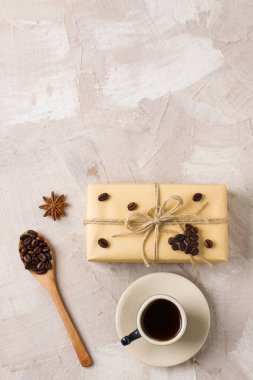 Mavi kahve fincanı, zanaat hediye kutusu sicim kahve kalp şekli dekorasyon, tahta kaşıkla kahve çekirdekleri, anason bej beton zemin üzerine. Kahve severler için bir hediye dekor fikri. Kopya alanı metin için yer.