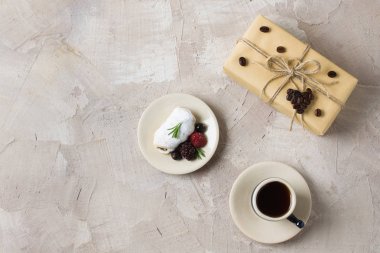 Mavi kahve, krem, böğürtlen ahududu siyah frenk üzümü biberiye ve pudra şekeri zanaat hediye kutusu ile rulo kahve kalp dekorasyon bej beton zemin üzerine sicim. Kopya alanı, metin için yer.