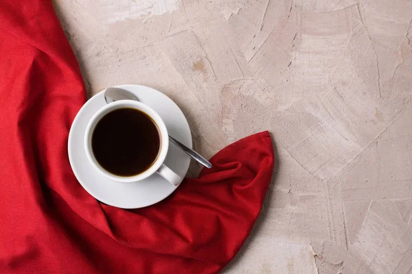 Beyaz fincan kahve ya da çay, bej beton zemin üzerine kırmızı peçete. Yatay yönlendirme, üstten görünüm, düz yatıyordu, kopya alanı, metin için yer.