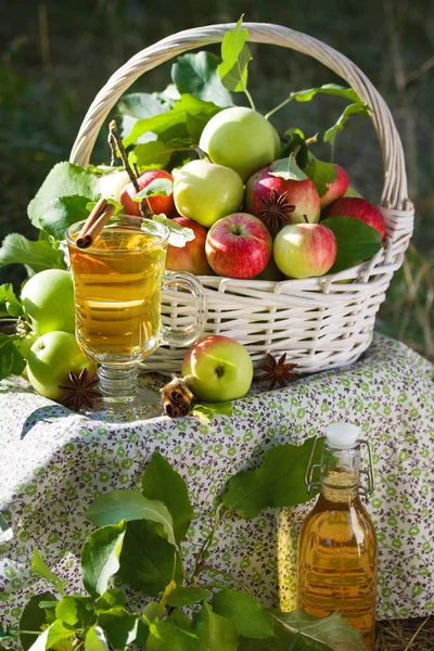 Yeşil ve kırmızı elma, elma suyu, meyve suyu veya cam şişe, sirke ile beyaz hasır sepet doğa arka planda, güneş ışığı bırakır. Yaz, sonbahar, taze elma hasat, hasat.