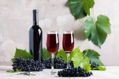 Mockup logo için iki bardak ve şişe kırmızı şarap. Kırmızı üzüm, yeşil yapraklar, bej renkli arka plan üzerinde tirbuşon. Kavram yeni hasat kırmızı üzüm, sonbahar.