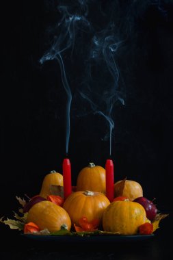Cadılar Bayramı, Şükran günü, kabak, elma, kuru yapraklar, physalis, kırmızı mumlar ve koyu arka plan üzerinde duman ile sonbahar natürmort kompozisyon. Tablo dekorasyon konsepti dikey yönlendirme kopya alanı.