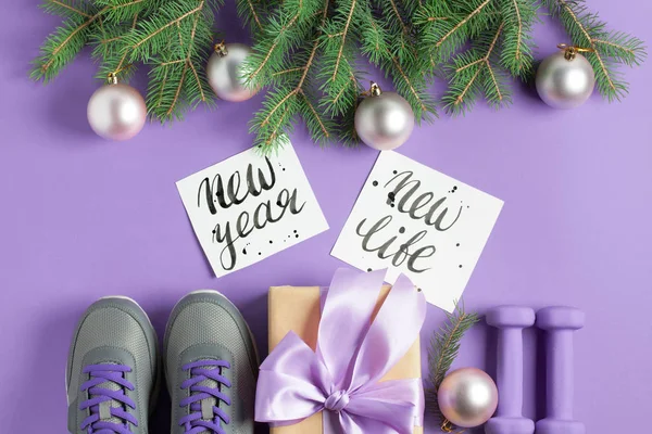 Noel spor düz gri Ayakkabı leylak yay Ladin ağaç dalları menekşe arka plan üzerinde yazı ile hediye kutusu mor dumbbells zanaat kompozisyon yatıyordu. Yeni yıl yeni yaşam konsepti. Üstten görünüm yatay.