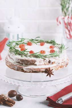 Noel kek camına rosemary ile dekore edilmiş stand ve kırmızı meyveler kurutulur. Baston şekerler, şişe süt, mum lamba ve köknar ağaçları ile kış tatil kompozisyon yağmurlama renkli.