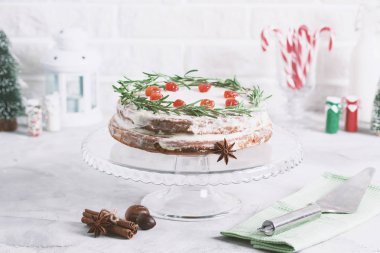 Noel kek camına rosemary ile dekore edilmiş stand ve kırmızı meyveler kurutulur. Baston şekerler, şişe süt, mum lamba ve köknar ağaçları ile kış tatil kompozisyon yağmurlama renkli.