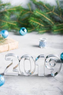 Mutlu yeni yıl 2019 kompozisyon metalik harfler, toplar, çam ağacı, zanaat hediye kutusunda mavi renkler, gri beton arka plan ile. Tebrik kartı.