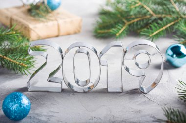 Mutlu yeni yıl 2019 kompozisyon metalik harfler, toplar, çam ağacı, zanaat hediye kutusunda mavi renkler, gri beton arka plan ile. Tebrik kartı.