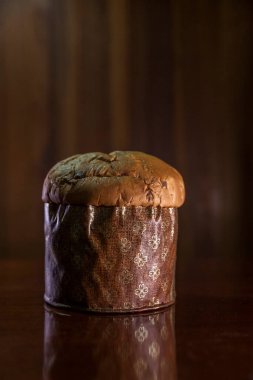 Panettone on the wooden table with textured brown woody background. Panettone concept. Space for text. Christmas concept.	