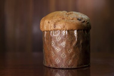 Panettone on the wooden table with textured brown woody background. Panettone concept. Space for text. Christmas concept.	