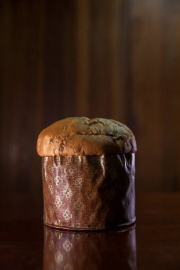 Panettone on the wooden table with textured brown woody background. Panettone concept. Space for text. Christmas concept.	