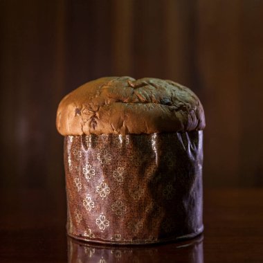 Panettone on the wooden table with textured brown woody background. Panettone concept. Space for text. Christmas concept.	