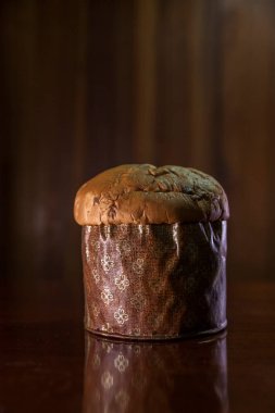 Panettone on the wooden table with textured brown woody background. Panettone concept. Space for text. Christmas concept.	