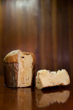 Panettone slice on the table. Panettone cut on wooden table and textured background. Panettone concept. Chocotone concept.	