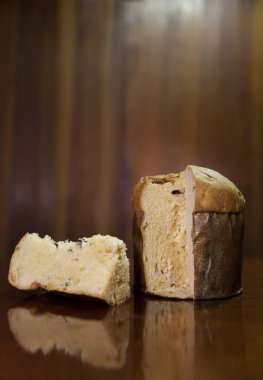 Panettone slice on the table. Panettone cut on wooden table and textured background. Panettone concept. Chocotone concept.	