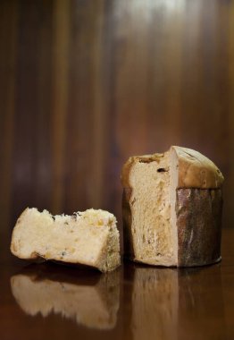 Panettone slice on the table. Panettone cut on wooden table and textured background. Panettone concept. Chocotone concept.	