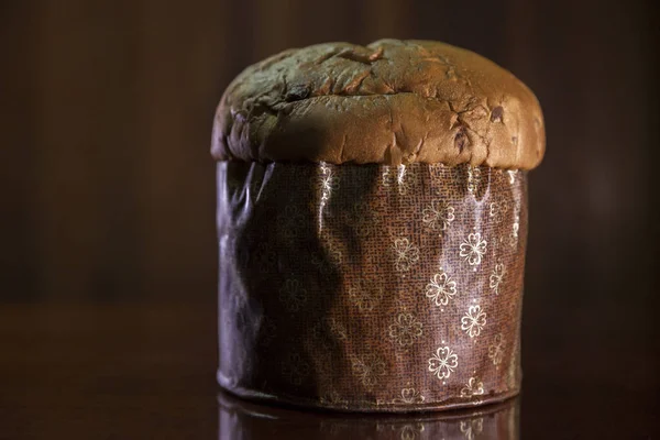 Panettone on the wooden table with textured brown woody background. Panettone concept. Space for text. Christmas concept.	