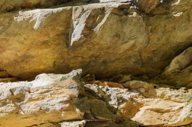 Görünür çatlaklar, katmanlaşma ve güneş ışığıyla aydınlatılmış, jeoloji, arkaplan veya tasarım kullanımına uygun doğal dokuya sahip kayalık yüzeyin ayrıntılı görünümü.