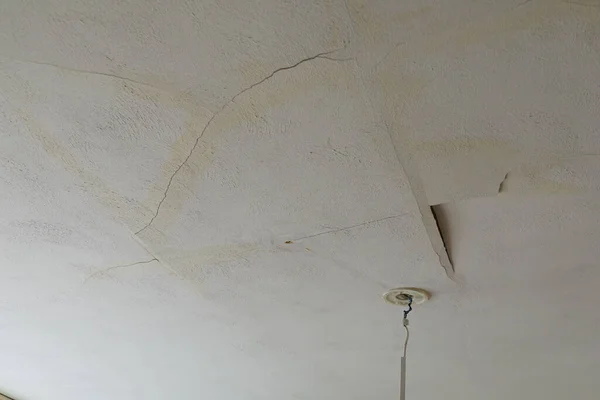 A plastered house ceiling broken by a water leak. rain or tap water caused serious damage.
