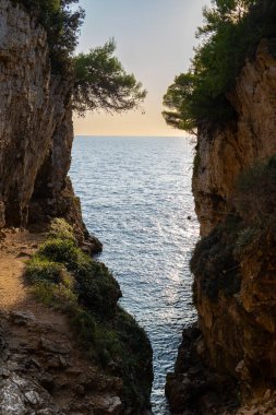 a path going through a cliff into the ocean