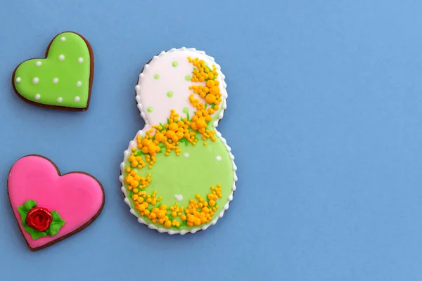 Kartpostal Kadınlar Günü, Mart 8, şekil sekiz, zencefilli çörek, mavi arka plan üzerinde çiçekler. Metin için boş alan. 