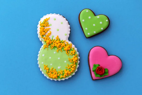 Kartpostal Kadınlar Günü, Mart 8, şekil sekiz, zencefilli çörek, mavi arka plan üzerinde çiçekler. Metin için boş alan. 