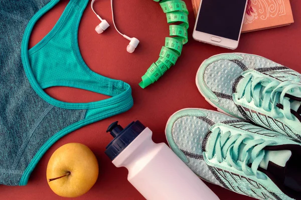 Accessories for sports on red background. Sneakers, water and earphones. Fitness, healthy and active lifestyles.