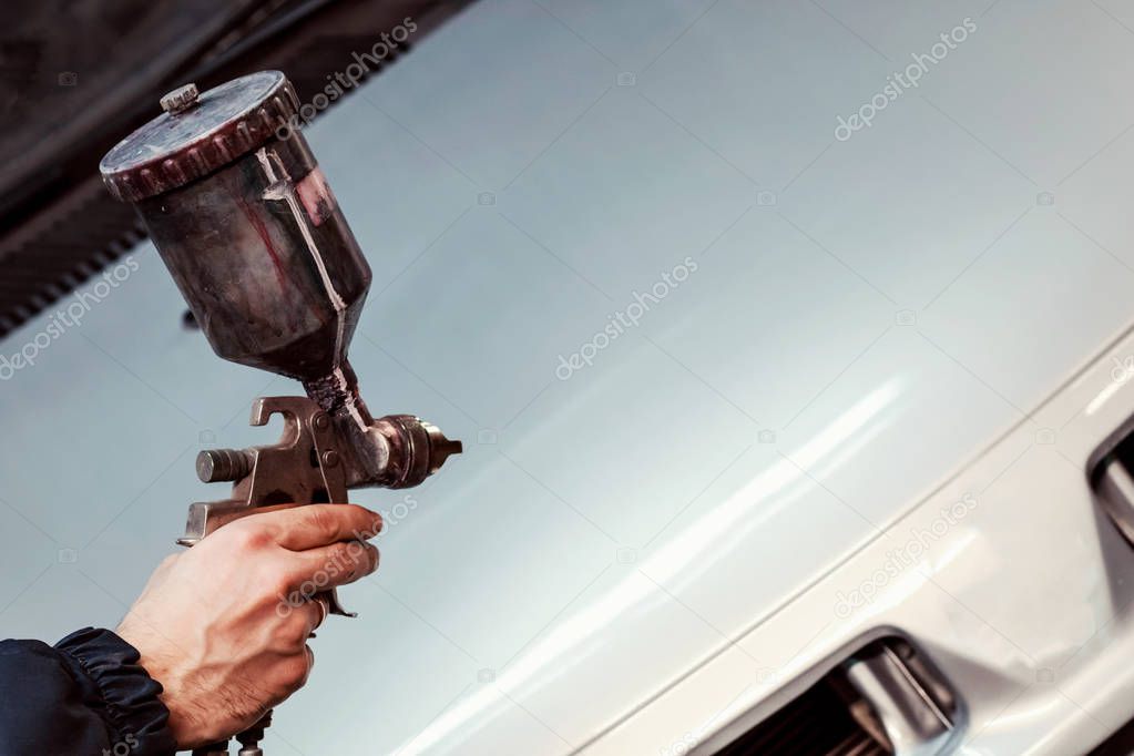 Auto mechanic worker painting car in paint chamber. Place for text.