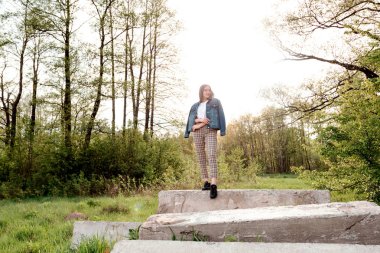 Yeşil yaz ve bahar ormanlarında kayaların üzerinde duran uzun kahverengi saçlı genç kız..