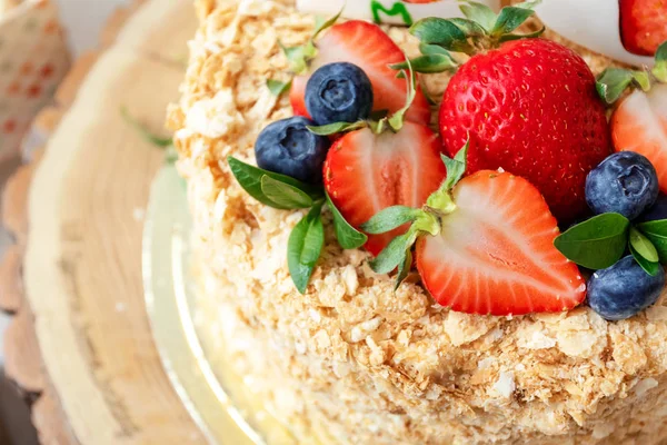 Ciasto miodowe ozdobione jasnymi truskawkami i jagodami. Uroczyste torty urodzinowe, weselne. Zbliżenie, makro. — Zdjęcie stockowe