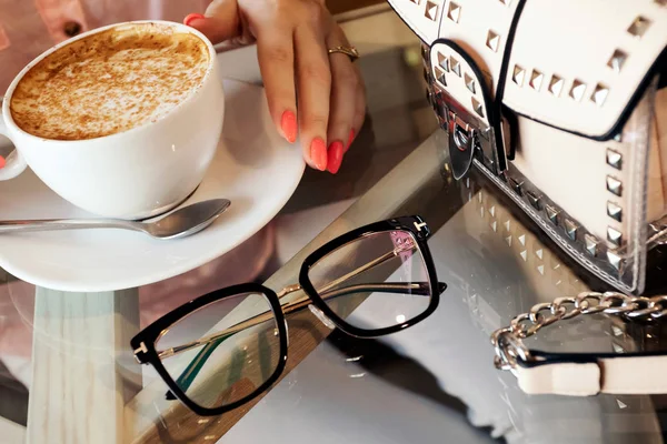 Sarışın kız kahve dükkanında, bardaklarda, el çantasında kahve içiyor. Blogger yatıyordu. Kafede sabah kahvesi.. Stok Resim