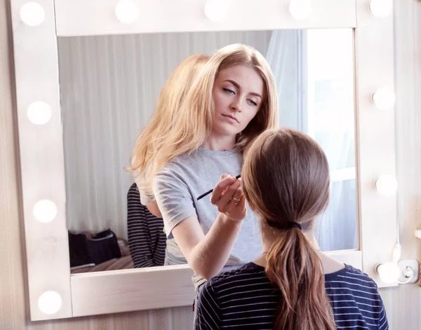 Maquillaje artista hace maquillaje de noche de niña de cabello castaño. Concepto de belleza, cuidado de la piel, maquillaje. —  Fotos de Stock