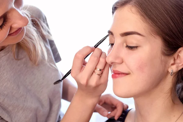 Make-up umělec malování krásné dívčí oční stíny. — Stock fotografie