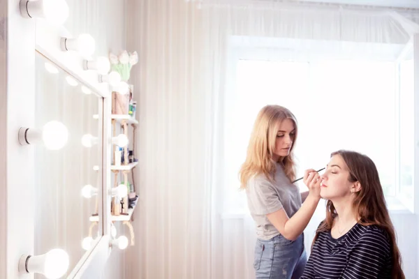 Make-up Artist macht Abend Make-up von jungen Mädchen mit braunen Haaren. Lässiges Outfit. Backstage des Prozesses. Platz für Text. — Stockfoto