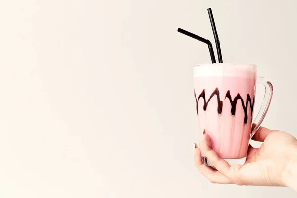 Milkshake rosa frio na caneca de vidro. Cocktail segura a mão feminina. Minimalismo. Lugar para texto . — Fotografia de Stock
