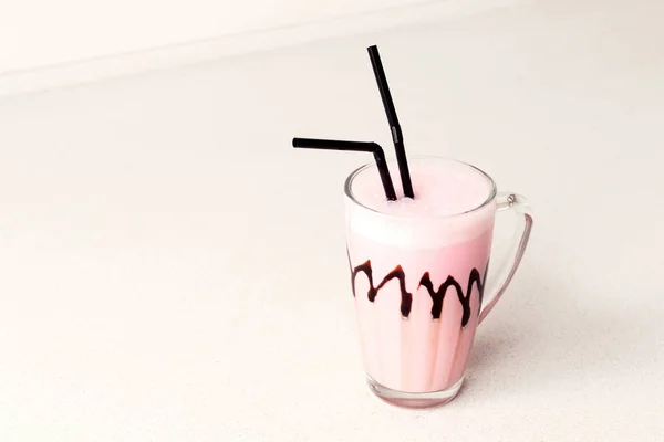 Cold pink milkshake in glass mug. Place for text.