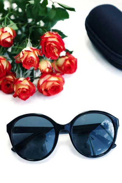Beyaz arka planda gül ve çantalı kadın güneş gözlüğü. Optik mağazası, gözlerinizi ultraviyole ışıktan koruyun. — Stok fotoğraf