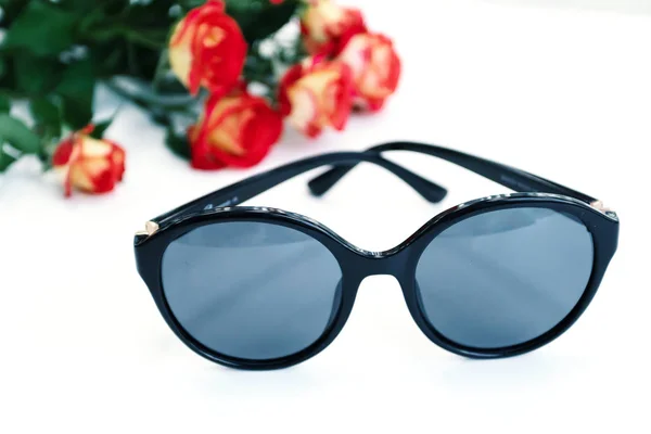 Women's sunglasses on white background with roses. Optics store, protect your eyes from UV light. — Stock Photo, Image