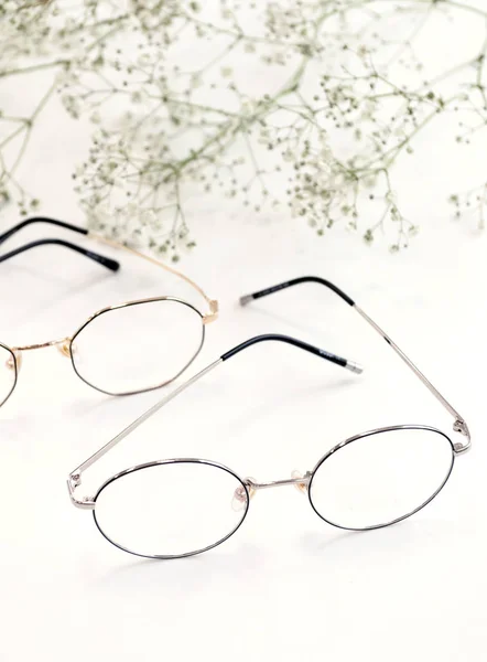 Beyaz çiçekli beyaz arka planda kadın gözlükleri. Optik mağaza, gözlerinizi korumak. — Stok fotoğraf