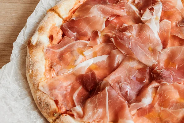 Ahşap arka planda jamonlu pizza.