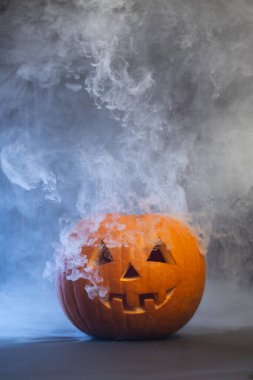 Gülümseyen bir yüzle Cadılar Bayramı balkabağı oymak, sis ile çevrili duman yaymak, mevsimsel şenlikler ve kutlamalar için ürkütücü atmosferi artırmak