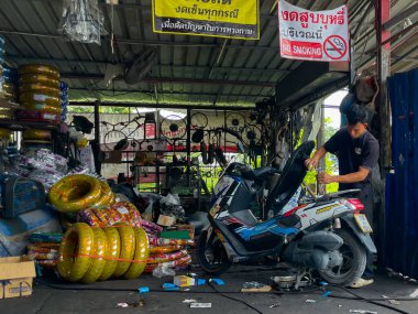 Thailand, Phuket  September 18, 2025: Mechanics repair motorcycles in a street workshop. A casual scene featuring traditional transport services.