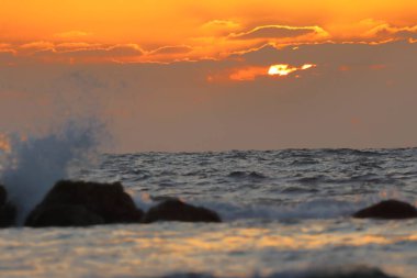 Denizde gün batımı Kayalara vuran dalgalarla.