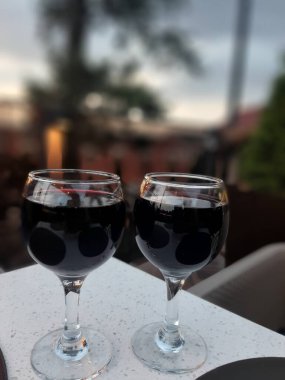 Tahta bir masanın üzerinde mum olan bir kadeh şarap.