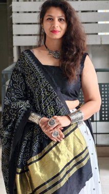 Zarif siyah beyaz Navratri Chaniya Choli 'li kadın altın lagdi patta sınırında dupatta ve oksitlenmiş mücevherler, modern festival modasını Garba ve geleneksel kutlamalar için mükemmel sergiliyor..