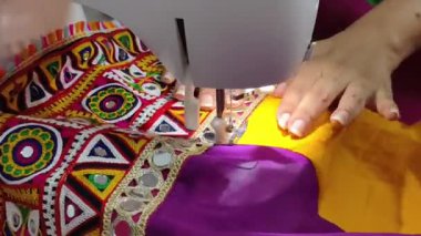 Renkli ayna işi işlemeli dantelin dikiş makinesiyle dikilip Navratri Chaniya Choli için geleneksel Hint tekstil sanatının sergilendiği bir lehenga. Gujarati takımı hazırlanıyor..