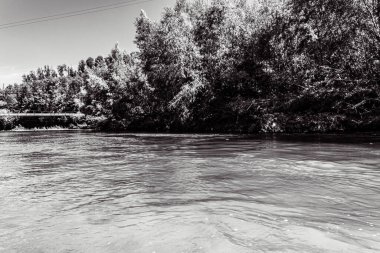 Nehrin ortasında köprüsü olan bir nehir, siyah ve beyaz.