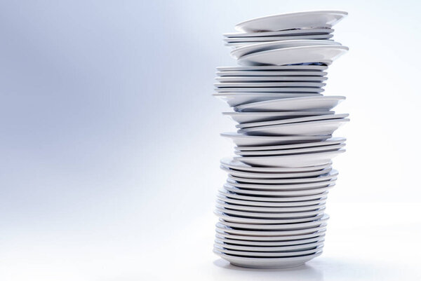 White dishes stacked together on white background.