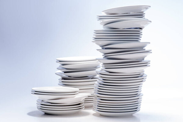 Many white plates stacked together on white background.
